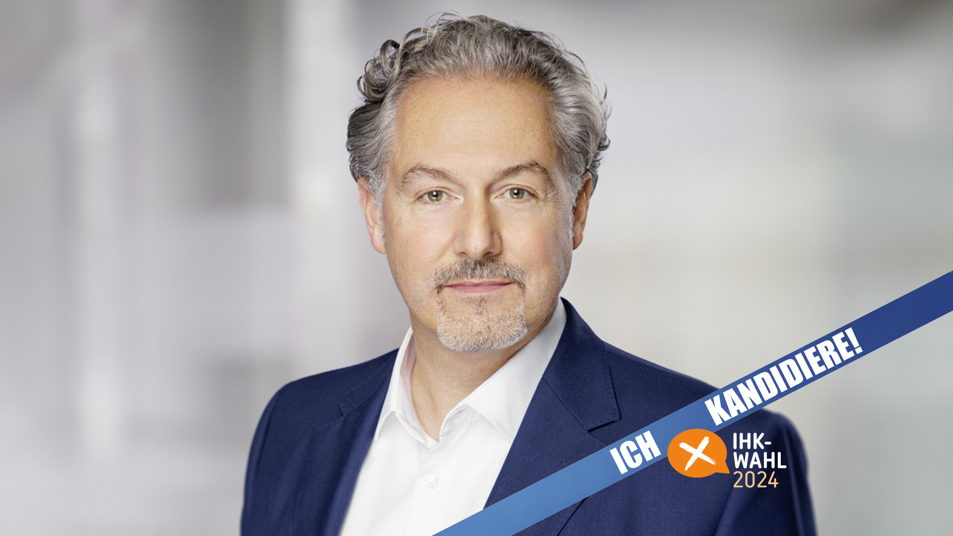Porträtfoto eines Mannes in Anzug und Hemd vor neutralem Hintergrund. Im Bildvordergrund verläuft ein blaues Banner mit der Aufschrift „Ich kandidiere! IHK-Wahl 2024“. Das Bild dient zur Ankündigung einer Kandidatur für die IHK-Wahl.